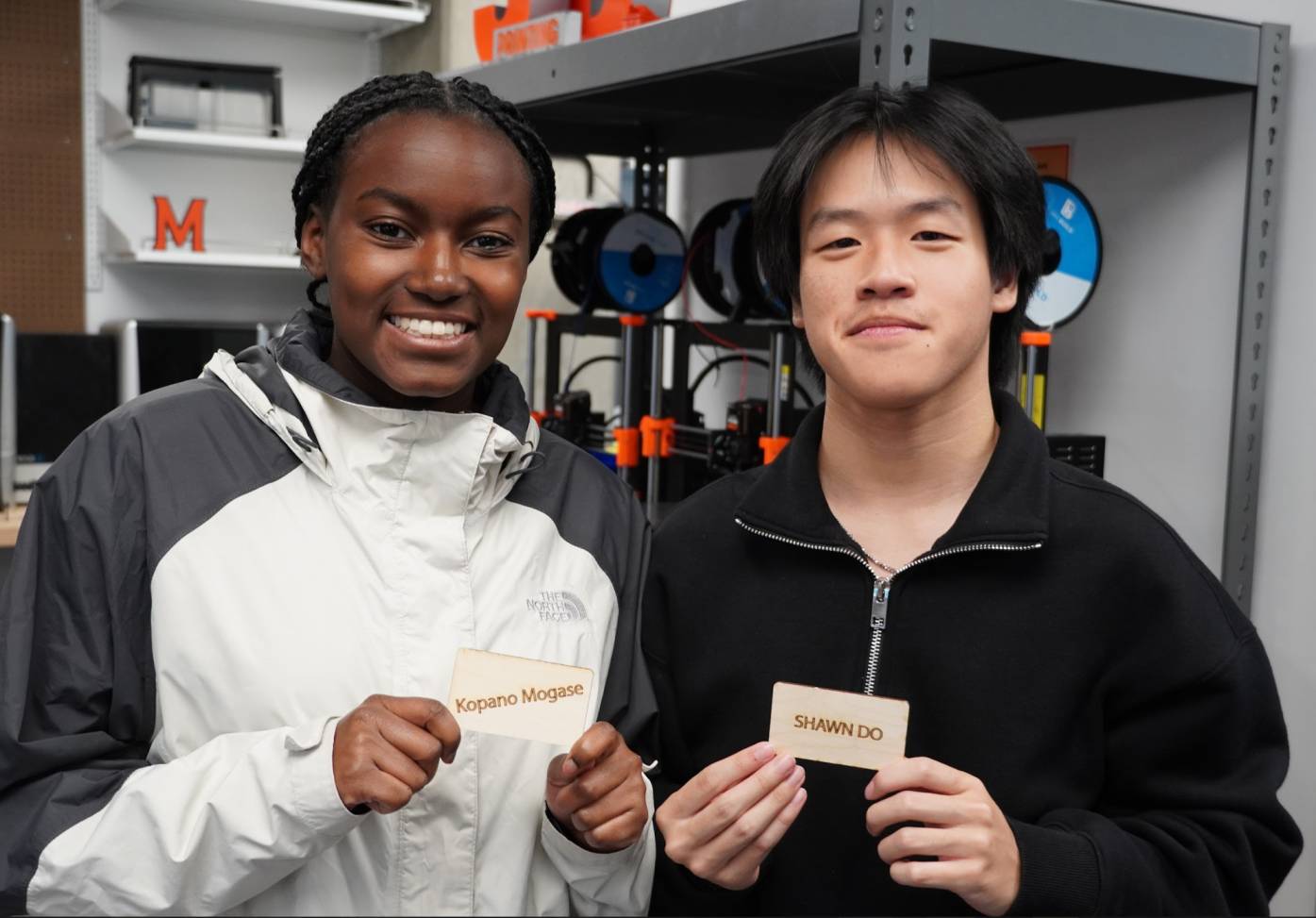 2 Students posing with their custom plywood name tags made in the workshop